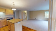 This single-floor residence offers a thoughtfully designed open-concept layout that seamlessly connects the kitchen and living areas. The kitchen is a functional highlight, featuring light maple cabinetry, granite countertops, stainless steel appliances including a refrigerator, range, microwave, and dishwasher, and a central island with additional counter space. Hardwood flooring runs throughout the kitchen and dining area, while plush carpeting extends across the spacious living room, which benefits from multiple large windows allowing generous natural light and outdoor views of surrounding greenery.

The bedrooms are carpeted and well-sized, each featuring large windows that invite natural light. The primary bedroom includes access to a walk-in closet, providing ample storage. The bathrooms are finished with light tile flooring, wood-toned vanity cabinetry, and white countertops. One bathroom features a full tub-shower combination with chrome fixtures and a mirrored medicine cabinet. A dedicated in-unit laundry area adds everyday convenience. Throughout, neutral warm tones, clean white trim, and consistent finishes create a cohesive and practical living environment.