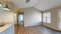 This well-designed 2-bedroom, 2-bathroom residence offers a comfortable and functional single-floor layout. The living room is a standout space, highlighted by striking vaulted ceilings that create an airy, open atmosphere. Wood-look flooring runs throughout the main living areas, adding warmth and durability, while a glass door and large window with blinds invite abundant natural light and provide outdoor access.

The kitchen is positioned adjacent to the living area and features white cabinetry, light countertops, and black appliances including a refrigerator, range, and microwave. Matching wood-look flooring continues seamlessly into this space.

Both bedrooms are carpeted for comfort and equipped with ceiling fans with light kits. Each room features windows with blinds that allow for natural light and privacy. The bedrooms offer a calm, neutral color palette consistent with the rest of the home.

The two bathrooms are clean and straightforward in design. One bathroom includes a full tub-shower combo with white tile surround, while the second features wood-look flooring, a wall-mounted vanity with a wide mirror, a natural light window, and open shelving for storage.

A dedicated closet provides additional organization, completing this practical and inviting residence.