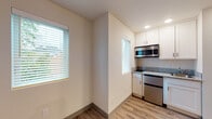 Located at 5603 SE Milwaukie Ave in Portland, Oregon, this single-floor unit offers a well-designed, modern interior with a clean, neutral aesthetic throughout. Wood-look plank flooring extends across the entire space, providing a warm and cohesive foundation. The main living area is brightened by multiple windows fitted with horizontal blinds, allowing natural light to filter in while maintaining privacy. A wall-mounted mini-split system provides efficient heating and cooling year-round.

The kitchenette is thoughtfully outfitted with white shaker-style cabinetry, granite-look countertops, a stainless steel microwave, and a compact stainless steel refrigerator, delivering functional cooking and storage capabilities within a modest footprint. Recessed lighting illuminates the kitchen area effectively. An adjacent walk-in closet with built-in shelving and hanging rods offers organized storage directly accessible from the main living space.

The bathroom features wood-look tile flooring, a walk-in shower with large-format gray tile surround, a compact floating vanity with a vessel-style sink, a wood-framed mirror, and a white storage cabinet. The overall design of the unit emphasizes efficient use of space, modern finishes, and practical amenities suited for everyday living.