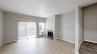 This two-floor residence offers a thoughtfully designed layout with a clean, neutral aesthetic throughout. The main living area is bright and open, featuring light wood-style flooring, a tile-surround fireplace with a white mantel, and a sliding glass door flanked by a window that invites generous natural light and outdoor views. Adjacent to the living area, the kitchen is well-appointed with gray shaker-style cabinetry, white quartz countertops, a classic white subway tile backsplash, and a full suite of stainless steel appliances including a refrigerator, range, microwave, and dishwasher. A peninsula provides additional counter space and serves as a natural division between the kitchen and living areas. A carpeted staircase connects the two floors, where the upper level continues the neutral palette with plush carpet flooring. Bedrooms are comfortable and well-lit, with large windows offering outdoor views and mirrored sliding-door closets providing ample storage. The bathrooms are finished with white quartz vanity tops, chrome fixtures, and a tub-shower combination clad in large-format gray stone-look tile. Throughout the space, textured walls, white trim, and a consistent warm-gray color scheme create a cohesive and inviting atmosphere.