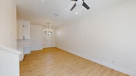 This thoughtfully designed two-story home offers a bright and modern living experience across two well-proportioned floors. The main level features an open-concept layout connecting the living room and dining area, both finished with light hardwood flooring and ceiling fans with recessed lighting overhead. A contemporary chandelier accents the entrance, setting a welcoming tone. The kitchen is outfitted with crisp white shaker cabinetry extending to the ceiling, white quartz countertops, a stainless steel sink with a matte black faucet, and stainless steel appliances — all accented by sleek black hardware. A dedicated laundry area and patio round out the ground floor. The staircase, featuring light wood treads and a warm wood handrail with white balusters, leads to the upper level, where the three bedrooms are located. Each bedroom is bright and airy with ceiling fans and large windows that bring in natural light and exterior views. The primary bedroom includes a spacious walk-in closet with built-in shelving and dual hanging rods. The primary bathroom is elegantly appointed with a double-sink vanity, white cabinetry with black hardware, framed mirrors, and a glass-enclosed walk-in shower with marble-style tile and a pebble-stone floor. Two additional closets provide ample storage throughout the home.