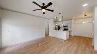 This contemporary apartment boasts an open floor plan that seamlessly integrates the living space and kitchen. The modern kitchen features white cabinetry, stainless steel appliances, and a functional island with pendant lighting. Throughout the space, light wood-look flooring creates a warm ambiance, complemented by crisp white walls. The living area is adorned with a stylish ceiling fan, while the bedroom offers ample natural light and closet space. The bathroom continues the modern aesthetic with a clean design and large mirror. High ceilings and recessed lighting enhance the overall sense of spaciousness in this well-appointed urban dwelling.