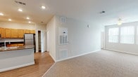This single-story residence offers a thoughtfully organized layout with distinct living, kitchen, bedroom, and bathroom areas. The living space is generously sized, featuring neutral-toned carpet, light gray walls, and a ceiling fan overhead. A large window allows natural light to fill the room, while a sliding vertical blind provides privacy. Dedicated HVAC vents and a utility panel on the wall ensure comfortable climate control throughout.

The kitchen is well-equipped with warm honey-toned cabinetry, dark granite countertops, and wood-look tile flooring. Stainless steel appliances include a gas range, over-the-range microwave, refrigerator, and dishwasher. Recessed lighting brightens the space, and a double-basin sink is conveniently positioned near the entry. A half bath is accessible just off the kitchen corridor.

The bedroom features plush carpet, a ceiling fan, and direct access to an ensuite bathroom complete with warm wood cabinetry and dark countertops. An in-unit laundry closet is conveniently located near the main entrance. Throughout the space, clean white trim and neutral finishes create a cohesive, move-in-ready aesthetic.