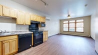 This one-bedroom, one-bathroom unit at 2195 W State St in Milwaukee, Wisconsin offers a practical and well-organized layout across a single floor. The open-concept kitchen and living area form the heart of the space, with durable hardwood-style flooring running throughout. The kitchen is equipped with light maple cabinetry offering ample upper and lower storage, granite-look countertops, and a full suite of black appliances including a refrigerator, electric range, built-in microwave, and dishwasher. Track lighting overhead provides functional illumination, while a wall-mounted mini-split unit supports climate control. The adjoining living area is bright and open, featuring a ceiling fan and a large multi-pane window fitted with wooden blinds that invite natural light. The bedroom is a comfortable size, carpeted for warmth, and includes its own ceiling fan, a wide window with natural light, and access to a dedicated walk-in closet with built-in shelving. A second room off the main area features hardwood-style flooring and a large window. The bathroom includes a wood-toned vanity with storage, a wall-mounted mirror cabinet, and a walk-in shower with grab bars and hardwood-style flooring throughout.