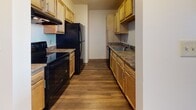 Located at 2 Museum Square in Lawrence, Massachusetts, this single-floor residential unit offers a thoughtfully designed layout with a range of functional spaces. Rich hardwood flooring flows consistently throughout, lending warmth and cohesion to the interior.

The open living area is spacious and bright, featuring a pass-through window that connects seamlessly to the galley-style kitchen. The kitchen is well-equipped with light wood cabinetry, granite-style countertops, black appliances including a refrigerator, range, and dishwasher, and ample upper and lower storage.

The bedrooms are generously sized, each featuring hardwood floors and large windows fitted with blinds that allow for natural light while maintaining privacy. The unit also includes a dedicated walk-in closet with built-in shelving and hanging rods, providing excellent storage capacity.

The full bathroom is clean and functional, featuring classic white tile with a subtle blue accent stripe in the tub/shower surround, mosaic tile flooring, a granite-topped vanity with wood cabinetry, and brushed nickel fixtures.

Overall, the unit presents a practical and comfortable living environment with consistent finishes throughout, ideally situated in the heart of Lawrence near Museum Square.