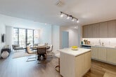 Located in Miramar, FL, this thoughtfully designed 2-bedroom, 1-bathroom residence offers a modern open-concept layout with clean lines and a neutral palette throughout. The combined kitchen and living area serves as the heart of the home, where a sleek kitchen features light wood cabinetry extending to the ceiling, white quartz countertops, stainless steel appliances including a wine cooler, and a central island with seating — ideal for both cooking and casual dining. Track lighting overhead enhances the bright, airy atmosphere. The dining area flows naturally into the living room, which is anchored by large floor-to-ceiling sliding glass doors opening to a balcony with lush palm tree views, flooding the space with natural light. The two bedrooms offer a comfortable retreat, each with plush carpeting and ceiling fans. The primary bedroom provides a well-proportioned layout, while the second bedroom features a window with outdoor views. Both bedrooms are served by dedicated closets. The bathroom is finished in crisp white tile and includes a soaking tub with shower. Wood-look flooring runs throughout the main living areas, tying together the cohesive, contemporary aesthetic of this well-appointed Miramar residence.