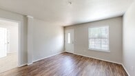 This single-story, 3-bedroom, 2-bathroom home offers a thoughtfully organized layout that balances functionality with a clean, neutral aesthetic throughout. The living room greets you at the front entry with warm wood-look laminate flooring, a textured ceiling, and a windowed front door that fills the space with natural light alongside a sizable side window fitted with blinds — creating a bright and welcoming atmosphere.

The galley-style kitchen features white upper cabinets, gray lower cabinets, white subway tile backsplash, and light countertops, complemented by black appliances including a range, microwave, and refrigerator. A skylight overhead adds additional brightness to this efficient cooking space.

The three bedrooms are carpeted for comfort, each with windows dressed in white blinds that provide natural light. The primary bedroom includes a walk-in closet with built-in shelving and hanging rods for ample storage.

The two bathrooms continue the home's clean, modern palette with white fixtures, a tub-shower combination with tiled surround, and vanities with white countertops. One bathroom conveniently opens to the in-unit laundry area, which houses a full-size washer and dryer with overhead shelving. The cohesive neutral tones and consistent finishes throughout the home contribute to a tidy, move-in-ready feel.