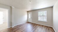 This single-story, 3-bedroom, 2-bathroom home offers a thoughtfully organized layout that balances functionality with a clean, neutral aesthetic throughout. The living room greets you at the front entry with warm wood-look laminate flooring, a textured ceiling, and a windowed front door that fills the space with natural light alongside a sizable side window fitted with blinds — creating a bright and welcoming atmosphere.

The galley-style kitchen features white upper cabinets, gray lower cabinets, white subway tile backsplash, and light countertops, complemented by black appliances including a range, microwave, and refrigerator. A skylight overhead adds additional brightness to this efficient cooking space.

The three bedrooms are carpeted for comfort, each with windows dressed in white blinds that provide natural light. The primary bedroom includes a walk-in closet with built-in shelving and hanging rods for ample storage.

The two bathrooms continue the home's clean, modern palette with white fixtures, a tub-shower combination with tiled surround, and vanities with white countertops. One bathroom conveniently opens to the in-unit laundry area, which houses a full-size washer and dryer with overhead shelving. The cohesive neutral tones and consistent finishes throughout the home contribute to a tidy, move-in-ready feel.