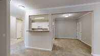 This single-floor residence offers a practical and comfortable layout encompassing two bedrooms and two full bathrooms. The interior is finished in a consistent neutral color palette throughout, contributing to a clean, cohesive aesthetic. Soft carpet covers the living areas and bedrooms, while light-toned ceramic tile floors are found in the kitchen and bathrooms.

The kitchen is efficiently designed with white cabinetry, dark countertops, white appliances including a refrigerator, range, and built-in microwave, and a pass-through opening that connects to the main living area. Crown molding accents the kitchen and living spaces, adding a refined architectural detail. The living area is generously sized, featuring a ceiling fan and a window that admits natural light.

Both bedrooms are carpeted and include windows with outdoor views of surrounding greenery. The primary bedroom is a comfortable size and benefits from crown molding. Each bathroom includes a tub/shower combination, a vanity with white cabinetry, tile flooring, and standard fixtures. A hallway connects the rooms, providing a logical and accessible flow throughout the residence.