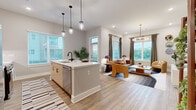 Located at 1015 N Alexander Street in Charlotte, NC, this thoughtfully designed two-bedroom, two-bathroom residence offers a cohesive open-concept floor plan with modern finishes throughout. The combined kitchen and living area serves as the heart of the home, where a sleek kitchen island with a white quartz countertop, matte black fixtures, and a bold teal tile backsplash anchors the space. Light wood cabinetry, stainless steel appliances, and pendant lighting over the island add both function and style. The living room is bright and welcoming, with multiple windows inviting natural light, a contemporary sputnik chandelier, and durable wood-look flooring that flows throughout the main living areas. The primary bedroom features plush carpet, natural views through large windows, and a walk-in closet with wire shelving. The second bedroom is equally well-sized with carpet flooring and easy hallway access. Both bathrooms are finished with wood-tone vanities, white quartz countertops, and matte black hardware; one features a full tiled tub-shower combination. A dedicated closet with double panel doors provides additional storage. Clean neutral walls, recessed lighting, and consistent design choices throughout create a cohesive, modern ambiance.