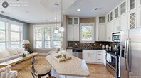 This thoughtfully designed 2-bedroom, 4-bathroom home in Durham, NC offers a comfortable and well-appointed single-floor layout. The open-concept kitchen is a standout feature, showcasing white shaker cabinetry with glass-front upper cabinets, a striking mosaic tile backsplash, dark granite countertops, stainless steel appliances, and a curved granite-topped island with bar seating — all illuminated by pendant lighting and generous natural light from multiple windows. The adjoining living room continues the bright, airy feel with large windows, warm hardwood-style flooring, and neutral wall tones that create a welcoming ambiance. Both bedrooms are carpeted and well-lit, with the primary bedroom offering expansive windows, ample space, and access to a walk-in closet. The bathrooms are finished with warm-toned tile work, including a glass-enclosed walk-in shower with mosaic accent tile detailing and a handheld fixture. Two well-sized closets provide generous storage throughout. A dedicated laundry area with a full-size washer and dryer adds everyday convenience. The overall design balances modern finishes with warm, neutral tones, resulting in a cohesive and inviting living environment.