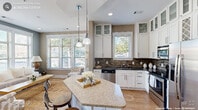 This thoughtfully designed 2-bedroom, 4-bathroom home in Durham, NC offers a comfortable and well-appointed single-floor layout. The open-concept kitchen is a standout feature, showcasing white shaker cabinetry with glass-front upper cabinets, a striking mosaic tile backsplash, dark granite countertops, stainless steel appliances, and a curved granite-topped island with bar seating — all illuminated by pendant lighting and generous natural light from multiple windows. The adjoining living room continues the bright, airy feel with large windows, warm hardwood-style flooring, and neutral wall tones that create a welcoming ambiance. Both bedrooms are carpeted and well-lit, with the primary bedroom offering expansive windows, ample space, and access to a walk-in closet. The bathrooms are finished with warm-toned tile work, including a glass-enclosed walk-in shower with mosaic accent tile detailing and a handheld fixture. Two well-sized closets provide generous storage throughout. A dedicated laundry area with a full-size washer and dryer adds everyday convenience. The overall design balances modern finishes with warm, neutral tones, resulting in a cohesive and inviting living environment.