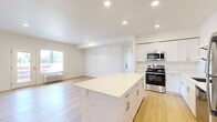 This single-story home offers four bedrooms, two bathrooms, and a thoughtfully designed layout that maximizes functionality. The open-concept kitchen and living area serves as the heart of the home, featuring light hardwood flooring that flows seamlessly throughout the space. The kitchen is well-appointed with white shaker-style cabinetry, light quartz countertops, a central island, stainless steel appliances including a gas range, microwave, and dishwasher, and open wall shelving for additional storage. Recessed lighting illuminates the space, enhancing its clean, modern aesthetic.

The living area is bright and airy, benefiting from natural light through a large window and a glass exterior door that opens to an outdoor area. Each bedroom is finished with the same light hardwood flooring and features windows with outdoor views, filling the rooms with natural light. The primary bedroom offers a comfortable, functional footprint.

The two bathrooms are finished with patterned tile flooring and light countertops. One bathroom includes a walk-in shower, while the second features a full soaking tub. Both maintain a clean, neutral palette consistent with the overall design of the home.