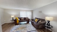 This single-floor residence offers a thoughtfully designed layout that balances comfort and functionality throughout its key living spaces. The living room serves as the heart of the home, featuring rich dark hardwood-style flooring, a textured ceiling, and a large window dressed with vertical blinds that fills the room with natural light and provides views of the surrounding greenery. The space comfortably accommodates dual seating areas, making it ideal for relaxing or entertaining.

Adjacent to the living room, the dedicated dining area is anchored by a stylish geometric pendant chandelier that adds a modern touch overhead. Dark hardwood-style flooring continues seamlessly into this space, creating a cohesive flow throughout.

The kitchen is efficiently arranged with white cabinetry, dark granite-style countertops, and white appliances including a refrigerator, electric range, built-in microwave, and dishwasher. Light tile flooring and ample cabinet storage make this a practical and clean cooking space.

The two bedrooms are comfortably sized, each featuring dark carpet flooring and vertical blinds. One bedroom includes a ceiling fan with light fixture. The full bathroom features white cabinetry, a dark granite vanity countertop, tile flooring, and a tub-shower combination, providing a clean and functional space.