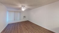 Unit #33 at 4525 Twain in San Diego is a single-floor residence designed with a clean, functional layout throughout. Wood-style flooring runs consistently across the living areas, bedrooms, and kitchen, providing a cohesive and easy-to-maintain surface. Textured ceilings are present throughout the unit.

The living area is open and well-lit, featuring a ceiling fan with integrated lighting and a wall-mounted air conditioning unit for year-round comfort. Vertical blinds on the windows allow for adjustable natural light. The space flows directly into the kitchen area, which is separated by a peninsula counter with a granite-style surface — ideal for casual dining or meal prep.

The kitchen is well-appointed with white cabinetry extending to the ceiling for generous storage, a double stainless steel sink, granite-style countertops, an electric range with overhead ventilation, and a stainless steel refrigerator.

The bedroom offers a ceiling fan with lighting, a window with vertical blinds, and wood-style flooring. A sliding mirrored closet door is also present in the hallway area.

The bathroom includes a white vanity with a granite-style countertop, a single sink, a wall mirror, and a separate compartment housing a shower-tub combination, keeping the layout practical and organized.