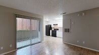 Located at 701 West Longspur Boulevard in Austin, TX, this single-floor unit offers an efficient and functional layout designed to maximize every square foot. The open-concept living and kitchen area forms the heart of the space, where wood-look flooring runs throughout, lending a warm and cohesive aesthetic. A large sliding glass door dressed with vertical blinds fills the living area with natural light and provides views of the surrounding outdoor greenery, creating a bright and inviting atmosphere. The textured ceiling adds a classic touch consistent throughout the unit. The kitchen is well-equipped with white cabinetry providing ample storage, light countertops, a double-basin stainless steel sink, a black refrigerator, a black electric range with overhead ventilation, and a dishwasher. The clean contrast of white cabinetry against the black appliances gives the kitchen a defined, practical character. A ceiling fan in the living area ensures comfortable airflow. The bathroom features a tiled tub-shower combination with chrome fixtures, maintaining a clean and functional design. A dedicated closet provides additional storage. This unit offers a straightforward, no-frills living experience in a convenient Austin location.