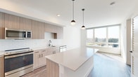 Located at 19888 40th Avenue West in Lynnwood, WA, this modern one-bedroom, one-bathroom residence offers a thoughtfully designed open-concept layout with contemporary finishes throughout. The kitchen is a standout feature, showcasing light wood cabinetry, white subway tile backsplash, quartz countertops, and a generously sized island with pendant lighting overhead. Stainless steel appliances — including a refrigerator, range, microwave, and dishwasher — complete the well-appointed space. Wood-style flooring flows seamlessly throughout the unit, adding warmth and continuity. A stacked in-unit washer and dryer provides added convenience. The living area benefits from large floor-to-ceiling windows that flood the space with natural light and offer pleasant views of the surrounding Lynnwood landscape. The bedroom is a comfortable, well-lit retreat featuring a large window with outdoor views and ample closet storage, served by two closets. The bathroom is clean and functional, featuring a soaking tub and shower combination, wood-finish vanity with quartz countertop, and matte black hardware accents. A hallway connects the rooms efficiently, keeping the layout practical and organized. This residence combines modern design with everyday functionality in a bright, well-planned setting.