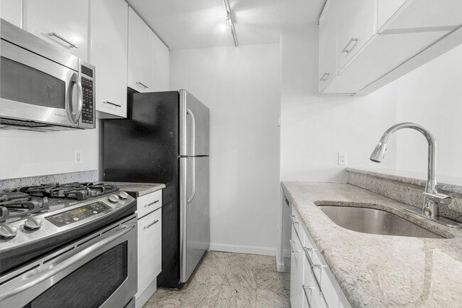 Kitchen with stainless steel appliances, granite counters, white cabinets with new drawer pulls. - 4 Martine Ave