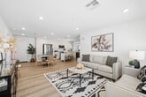 Located in Lancaster, CA, this well-appointed single-story home offers three bedrooms and two bathrooms across a thoughtfully designed floor plan. The open-concept kitchen and living area serves as the heart of the home, featuring crisp white cabinetry extending to the ceiling, stainless steel appliances including a range, microwave, and refrigerator, and a central island with a butcher block top and seating. Light wood-style flooring flows throughout, enhancing the clean, modern aesthetic. The living room is bright and welcoming, with recessed lighting, large windows that invite natural light, and a neutral color palette that complements any decor. The primary bedroom is a comfortable retreat with windows on multiple walls, filled with natural light, and accompanied by a dedicated walk-in closet featuring built-in shelving and hanging rods. The en-suite primary bathroom includes a white vanity and a separate water closet. A second full bathroom offers a tub-shower combination with white tile surround and built-in open shelving. Additional bedrooms are well-sized with ample natural light. Throughout the home, the consistent use of light tones, recessed lighting, and wood-look flooring creates a cohesive, airy ambiance ideal for modern living.
