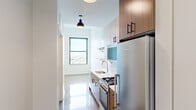 Located at 1133 W Lawrence Ave in Chicago's Uptown neighborhood, this thoughtfully designed single-floor unit blends modern finishes with functional layout. The galley-style kitchen is a standout feature, outfitted with stainless steel appliances including a gas range and full-size refrigerator, white subway tile backsplash, clean white lower cabinetry paired with warm wood-toned upper cabinets, open shelving, and a stainless sink. Pendant lighting with matte black industrial-style fixtures adds character overhead. Polished terrazzo-style flooring runs throughout the space, reflecting light and lending a sleek, contemporary feel. A window at the end of the kitchen and dining area frames elevated views of the Chicago skyline and surrounding cityscape, filling the space with natural light. The bathroom is clean and minimal, featuring white walls, a glass-enclosed shower, and consistent flooring that ties the design together cohesively. The open living and dining area offers a bright, versatile space with crisp white walls and ample room to configure furnishings to suit various needs. The overall aesthetic is modern and understated, with carefully chosen finishes that create a cohesive and contemporary urban living environment.