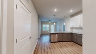 Located at 5697 SW 49th Rd in Ocala, Florida, this thoughtfully designed 2-bedroom, 2-bathroom residence offers a cohesive blend of modern finishes and functional living spaces across a single floor. The open-concept kitchen serves as the centerpiece of the home, showcasing granite countertops, a large peninsula island with pendant lighting, two-tone cabinetry with white uppers and gray lowers, and a full suite of stainless steel appliances including a refrigerator, range, and microwave. Light wood-look flooring flows throughout the main living areas, enhancing the bright and airy atmosphere. The living area benefits from natural light through multiple windows and is complemented by a ceiling fan overhead. Both bedrooms feature plush carpeting, and the spacious primary bedroom connects to a walk-in closet with wire shelving systems and a private en-suite bathroom. The primary bath offers a double granite-topped vanity, wood-toned cabinetry, and a glass-enclosed walk-in shower. The second bathroom mirrors the refined finishes with a granite vanity and a tub-shower combination with tile surround. Each bedroom includes its own dedicated closet for ample storage. The overall design maintains a clean, contemporary aesthetic throughout.
