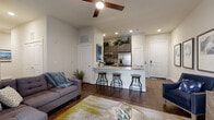 This thoughtfully designed single-floor amenity space combines contemporary architecture with a wide range of resident-focused features. The centerpiece is a spacious open-air lounge area beneath a striking ceiling of alternating dark and light exposed beams, fitted with pendant track lighting and ceiling fans. Large floor-to-ceiling glass walls blur the boundary between indoors and out, offering direct views of the pool and surrounding courtyard. Stone-tiled flooring anchors the space with a neutral, sophisticated palette throughout.

A glass-enclosed private office provides a quiet workspace, featuring a built-in desk and horizontal accent tiling. Nearby, a sleek service counter with white quartz surfaces and dark cabinetry opens to a well-lit business lounge with workstations, ideal for remote work. The entertainment lounge features warm wood-panel walls, wall-mounted flat-screen televisions, plush modular seating, and a glimpse of a billiards area behind a slatted glass partition.

The fitness center is generously equipped with a full array of strength and cardio machines, polished concrete flooring, and mirrored glass walls. Outside, a covered terrace with the same bold beam ceiling leads to a landscaped courtyard with comfortable outdoor seating nestled among lush greenery and multi-story building facades.