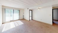 Located at 301 S Highland Ave in Pittsburgh's Highland Park neighborhood, this single-floor unit offers a straightforward and functional layout well-suited for comfortable everyday living. The living area is generously sized, featuring neutral wall-to-wall carpeting, a tiled ceiling, and a large sliding glass door fitted with vertical blinds that invites abundant natural light and provides access to the outdoors. An adjacent room, also carpeted and bathed in sunlight through a wide window with vertical blinds, serves well as a bedroom or flexible living space. A second carpeted room offers similar bright, airy qualities with its own large window. The kitchen is equipped with warm oak cabinetry, light-toned countertops, a stainless steel sink, a white electric range with overhead ventilation, a dishwasher, and tile flooring — providing ample storage and a practical cooking environment. Two bathrooms complete the unit: one features a full tub-shower combination with white tile surround and chrome fixtures, while the other includes a vanity with oak cabinetry, a white countertop, tile flooring, and a toilet. Throughout the space, clean white walls and consistent finishes create a bright, neutral atmosphere that is move-in ready and highly adaptable.