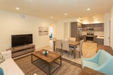 Located at 7043 Jordan Ave in the Canoga Park neighborhood of Los Angeles, this modern single-floor unit offers a thoughtfully designed open-concept layout with clean lines and contemporary finishes throughout. Light wood-tone flooring flows seamlessly from room to room, complementing the crisp white walls and recessed lighting that give the space a bright, airy feel.

The open living and dining area forms the heart of the unit, featuring a comfortable seating arrangement, a media console, and a rustic wood dining table with upholstered chairs — all anchored by a herringbone-patterned area rug. The space transitions effortlessly into a well-appointed kitchen, outfitted with sleek gray cabinetry extending to the ceiling, white quartz countertops, a stainless steel sink, and a full suite of stainless steel appliances including a gas range, built-in microwave, and French door refrigerator.

The bedroom is a serene retreat, featuring sliding glass doors that open to a private balcony, allowing natural light to fill the room. The bathroom is finished in a clean, minimalist style with a white vanity, large mirror, gray cabinetry, and a glass-enclosed shower-tub combination. A dedicated hallway connects the living spaces to the private quarters, ensuring a functional and comfortable flow throughout.