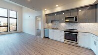 Located at 1677 N Main St in Walnut Creek, CA, this single-floor unit offers a thoughtfully designed open-concept layout with contemporary finishes throughout. Light wood-tone luxury vinyl plank flooring extends across the main living and kitchen areas, creating a clean, cohesive aesthetic that enhances the sense of openness.

The kitchen is a standout feature, outfitted with a full suite of stainless steel appliances including a French door refrigerator, slide-in range, built-in microwave, and dishwasher. Two-tone cabinetry pairs glossy gray upper cabinets with crisp white lower cabinets, complemented by a decorative mosaic tile backsplash and recessed lighting overhead.

The bedrooms are carpeted for comfort and feature large black-framed windows that invite generous natural light and offer elevated views of the surrounding Walnut Creek neighborhood. Recessed ceiling lighting and clean white walls contribute to the bright, modern ambiance throughout.

Two bathrooms serve the unit, each finished with large-format tile flooring and marble-style tile surrounds. One bathroom features a glass-enclosed walk-in shower, while the second includes a soaking tub and a vanity with ample cabinet storage. Both reflect a polished, contemporary design sensibility consistent with the rest of the space.