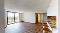 This single-floor residence offers a thoughtfully designed layout that balances open communal spaces with comfortable private quarters. The living area is spacious and bright, anchored by wood-look plank flooring and large floor-to-ceiling sliding glass doors that open to a private balcony, flooding the room with natural light and framing sweeping views of the surrounding cityscape and greenery.

The kitchen is efficiently organized in a galley-style configuration, featuring warm honey-toned wood cabinetry, granite countertops, a decorative mosaic tile backsplash, and black appliances. A peninsula with bar seating for three connects the kitchen to the main living area, creating a seamless space ideal for casual dining or entertaining.

The bedrooms are carpeted for comfort and include generous closet space with built-in shelving. Each room benefits from windows that continue the residence's theme of natural light and elevated views. The primary bathroom includes a double-sink vanity with granite countertops, warm wood cabinetry, and tile flooring, while the second bathroom features a clean, white tub-shower combination with tile flooring. Throughout the unit, warm wood trim and neutral tones create a cohesive, welcoming ambiance.