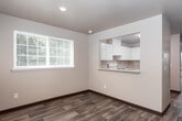 This two-floor residence offers a practical and well-organized layout with a variety of functional living spaces. The main living area is bright and open, featuring wood-style plank flooring, recessed lighting, and multiple windows that invite natural light and offer views of surrounding greenery. A pass-through opening connects the living space to the kitchen, which is equipped with white cabinetry, laminate countertops, a stainless steel sink, and a white electric range with overhead ventilation. The layout promotes an efficient workflow while maintaining visual connection to the adjacent living area.

A separate, generously sized living room on another level features sliding glass doors that open to a private balcony, further enhancing natural light and outdoor access. The carpeted bedrooms are comfortable and well-lit, each featuring multiple windows with views of mature trees, creating a serene atmosphere. At least one bedroom includes direct access to a bathroom.

The bathrooms are cleanly finished with wood-style flooring, a single vanity with a large mirror, and a shower-tub combination. A dedicated laundry area houses a full-sized washer and dryer with overhead wire shelving, adding significant convenience. Throughout the space, neutral tones and textured walls create a cohesive, understated aesthetic.