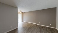Located at 6252 Corbly St in Cincinnati, Ohio, this single-floor unit offers a well-maintained and thoughtfully updated interior. The living area is generously sized, featuring durable hardwood-style flooring in a warm, neutral tone, taupe-painted walls, and a textured ceiling. A ceiling fan with a light fixture is centrally positioned, while a baseboard heating system runs along the wall. Vertical blinds frame a sliding glass door that allows natural light to fill the space. A secondary room with hardwood-style flooring and a window fitted with horizontal blinds provides versatile use as a bedroom or office, offering pleasant outdoor views and a calm, light-filled atmosphere. The kitchen is efficiently laid out with clean white cabinetry, granite-style countertops, a stainless steel sink with a modern pull-down faucet, a stainless steel refrigerator, and an electric range. Light vinyl plank flooring completes the kitchen's fresh, contemporary look. The bathroom is neatly appointed with a granite-top vanity, an illuminated mirror, and a full tub-shower combination with clean white surrounds. Neutral grey tones and updated fixtures throughout the unit create a cohesive, move-in ready aesthetic.