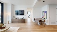 Located in the heart of Midtown Atlanta, this sleek 2-bedroom, 4-bathroom residence offers a refined urban living experience defined by contemporary design and breathtaking city views. Light wide-plank hardwood flooring flows throughout, complementing a clean, modern aesthetic anchored by crisp white walls and black-framed floor-to-ceiling windows.

The open-concept living and dining area is bright and spacious, with expansive glazing that frames sweeping Atlanta skyline panoramas and opens directly onto a private balcony. The kitchen is outfitted with dark cabinetry reaching to the ceiling, a herringbone-patterned tile backsplash, white quartz countertops, and a full suite of stainless steel appliances.

The primary bedroom is a generous retreat featuring wraparound floor-to-ceiling windows on two walls, a ceiling fan, and dramatic elevated views of the Atlanta skyline. The second bedroom is equally well-appointed, offering its own large window with city views and light hardwood flooring. Both bedrooms include dedicated closets.

The four bathrooms showcase a cohesive design language with large-format neutral tiles, glass-enclosed walk-in showers, hexagonal tile flooring, teak shower benches, and matte black fixtures. In-unit laundry adds everyday convenience, while two hallways connect the layout efficiently.