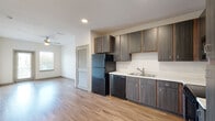 Located at 3036 Philips Hwy in Jacksonville, FL, this one-bedroom, one-bathroom residence offers a thoughtfully designed single-floor layout that maximizes every square foot. The open-concept living and kitchen area is anchored by warm-toned luxury vinyl plank flooring that flows throughout the main living spaces, creating a cohesive and contemporary feel. Natural light fills the living room through a large window and glass-panel door, complemented by a ceiling fan overhead.

The kitchen is well-appointed with dark wood-grain cabinetry extending to the ceiling for ample storage, white countertops, a double-basin sink, and a full suite of black appliances including a refrigerator, dishwasher, electric range, and over-the-range microwave. A louvered door off the kitchen provides convenient access to additional storage.

The bedroom features plush carpeting, a ceiling fan, and a window with natural views. It connects to a generously sized walk-in closet with wire shelving systems for organized storage. The full bathroom includes a double-sink vanity with dark cabinetry, a large mirror, wood-look flooring, and a full soaking tub with shower. Neutral tones and clean finishes throughout give the space a bright, move-in-ready appeal.