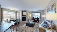 Located in Superior, Colorado, this thoughtfully designed one-bedroom, two-bathroom residence offers a well-appointed single-floor layout that maximizes every square foot. The open-concept living and dining area serves as the heart of the home, anchored by a corner fireplace with a classic mantle and flanked by multiple windows that flood the space with natural light and offer views of the surrounding landscape. Wood-style flooring flows throughout the main living areas, complementing the neutral, contemporary color palette. Built-in shelving adds both function and visual interest to the living room. The dining nook features large bay-style windows framed by elegant drapes, creating a bright and inviting setting. The kitchen is efficiently designed with white cabinetry, dark countertops, stainless steel appliances, a tile backsplash, and a peninsula breakfast bar with seating. The spacious primary bedroom features plush carpeting, a bold accent wall, and a dedicated closet. Two full bathrooms serve the residence — one with a white-vanity and dark countertop, and another featuring a full soaking tub with clean white tile surround. A hallway connects the private quarters to the main living spaces, completing this well-organized and stylish home.