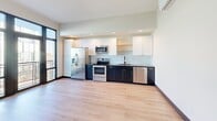 Located in Tulsa's historic Greenwood District, this thoughtfully designed one-bedroom, three-bathroom residence offers a refined, contemporary living experience on a single floor. Light-toned hardwood flooring and dark baseboards run throughout, creating a clean, modern aesthetic that ties the entire space together.

The open kitchen is a standout feature, showcasing a striking two-tone design with dark lower cabinetry and crisp white upper cabinets. Stainless steel appliances — including a refrigerator, electric range, microwave, and dishwasher — are complemented by a light tile backsplash and ample counter space. A wall-mounted mini-split unit provides efficient climate control.

The bedroom offers generous natural light through large floor-to-ceiling windows and glass doors that open to a private balcony, filling the room with brightness and outdoor views. An open closet with built-in shelving provides practical storage.

All three bathrooms are finished with classic white hexagonal tile flooring and dark accents. One bathroom features a floating vanity with gold fixtures and a wall sconce, while another includes a walk-in shower with subway tile surround. A third, more spacious bathroom offers a soaking tub and additional storage. Throughout the home, matte black hardware details add a cohesive, modern touch.