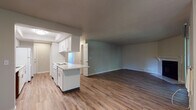 Located in Spokane Valley, Washington, this single-floor unit at 12407–12415 East 12th Avenue offers a practical and comfortable layout designed for everyday living. The open-concept living and dining area is finished with durable wood-look plank flooring and features a sliding glass door that opens to a private deck, filling the space with natural light and tree-lined views. A wall-mounted air conditioning unit and baseboard heating ensure year-round comfort.

The galley-style kitchen is thoughtfully designed with white shaker cabinetry, light countertops, a white appliance suite including an electric range and refrigerator, and a built-in dishwasher. A pass-through peninsula connects the kitchen to the living area, enhancing the open feel of the space.

A central hallway with a built-in open shelving unit leads to the bedrooms, both of which feature plush carpeting, baseboard heating, and windows that bring in natural light. The primary bedroom includes direct access to a full bathroom and a separate laundry closet with in-unit washer and dryer hookups. The bathroom features white cabinetry, a wide vanity with a framed mirror, and a shower-tub combination. A second bathroom with wood-look flooring serves the remainder of the unit. Textured ceilings and clean white trim complete the interior throughout.