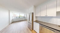 Located on the 7th floor at 155 Wellesley Street East in Toronto's vibrant Church-Wellesley Village, this one-bedroom, one-bathroom unit offers a bright and functional layout across a generously sized single floor. Light wood laminate flooring runs throughout, creating a clean, cohesive aesthetic complemented by crisp white walls.

The kitchen is outfitted with stainless steel appliances including an LG range and over-the-range microwave, white shaker-style cabinetry, and a classic white subway tile backsplash. It connects seamlessly to the hallway entrance, providing an efficient flow into the main living areas.

The spacious living room is bathed in natural light through floor-to-ceiling windows that overlook the surrounding cityscape, with a baseboard heating unit running along the window wall. Access to the balcony extends the living space outward, offering open views of the Toronto skyline and neighbouring architecture.

The bedroom features mirrored sliding closet doors that reflect light and enhance the sense of space, while the full bathroom is finished with white subway tile surrounding the bathtub, neutral stone-look floor tiles, a vanity with an integrated sink, and a large mirror — all kept bright by a window above the tub.

A hallway connects all rooms with ease, completing this well-appointed urban residence.