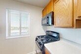 Located at 2500 Queens Chapel Rd in Hyattsville, MD, this two-bedroom, one-bathroom residence offers a straightforward and functional single-floor layout. The interior is finished in a clean, neutral palette throughout, creating a bright and cohesive atmosphere.

The kitchen features light wood cabinetry, a gas range with an over-the-range microwave, and light-toned countertops. A window above the counter area allows natural light to fill the space, and durable hard-surface flooring completes the room.

Both bedrooms are carpeted in a warm neutral tone and feature windows with horizontal blinds that frame views of surrounding greenery. The primary bedroom is generously sized and includes two closets, providing ample storage. The second bedroom also benefits from natural light and its own closet space.

The bathroom is finished with white tile wainscoting, light tile flooring, a white vanity with a medicine cabinet mirror, and a well-lit vanity bar — giving the room a clean and bright character.

A hallway connects the main living areas, and an additional closet offers further storage. The open living area is carpeted and offers a spacious, versatile footprint well-suited for a variety of furniture arrangements. Overall, the residence presents a clean, move-in ready environment with consistent finishes throughout.
