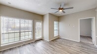 This single-floor unit presents a clean, neutral aesthetic throughout, with warm beige walls and white trim creating a cohesive, move-in-ready environment. The living area is a standout feature, benefiting from multiple windows fitted with horizontal blinds and a glass-paneled exterior door that invites generous natural light. A ceiling fan with a built-in light fixture adds both function and comfort to the space. Wood-look plank flooring extends across the main living areas, offering durability and a modern visual appeal.

The galley-style kitchen is efficiently laid out along a single corridor, featuring gray cabinetry with contemporary hardware, white countertops, and stainless steel appliances including a refrigerator, electric range, and dishwasher. Light-toned flooring continues seamlessly into this space.

The bedrooms are finished with plush carpeting and neutral walls, providing a quieter, softer environment. Natural light filters in through blinds-equipped windows in each room. The bathroom includes a full-size soaking tub with an overhead shower, complemented by wood-look tile flooring and clean white fixtures. The textured ceilings are consistent throughout, adding a subtle dimensional quality to the overall interior.