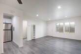 Located on Delaware Street in Huntington Beach, California, this single-story home showcases a clean, modern aesthetic carried consistently throughout every room. Light-toned luxury vinyl plank flooring runs throughout the entire space, lending a cohesive and contemporary feel underfoot while reflecting natural light from the numerous windows fitted with horizontal blinds.

The living area is bright and open, with recessed lighting and a ceiling fan complementing natural light that filters in through a large front-facing window. The layout flows naturally into the additional rooms, each of which features a ceiling fan with integrated lighting, neutral cream walls, and ample window space that brings in views of the surrounding greenery.

The kitchen stands out as a well-appointed space featuring white shaker-style cabinetry extending to the ceiling, quartz-look countertops, a stainless steel gas range, and an over-the-range microwave. Multiple windows allow natural light to brighten the workspace, and a secondary door provides convenient exterior access.

The bathroom is finished with clean white subway tile surrounding the tub-shower combination, accented by brushed gold fixtures that add a warm, refined touch. A frosted window above the tub provides privacy while maintaining natural light. Overall, the home presents a fresh, move-in-ready interior with consistent modern upgrades throughout.