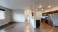 Located at 16511 East Sprague Avenue in Spokane Valley, WA, Unit F7 is a thoughtfully designed single-floor residence featuring a clean, contemporary aesthetic throughout. The open-concept living area is anchored by rich hardwood-style flooring that extends through the main living and kitchen spaces, while large windows and a glass exterior door invite natural light and provide views of the surrounding area. A wall-mounted A/C unit and baseboard heating ensure year-round comfort.

The kitchen is well-appointed with dark espresso cabinetry, stainless steel appliances including a refrigerator, electric range, and built-in microwave, along with a double sink and ample counter space. A peninsula with pendant lighting separates the kitchen from the living area, creating a natural and functional flow.

The bedrooms are carpeted for warmth and comfort, each offering generous proportions and access to natural light. The unit includes two full bathrooms — one featuring tile flooring and a tub/shower combination, and the other with wood-style flooring, a dark-toned vanity with mosaic tile backsplash, and a tub/shower. A central hallway connects the private and shared spaces efficiently, completing this functional and attractive residential unit.