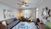 Located at Hurstbourne Estates, this single-story residence offers a cohesive and functional layout across several well-appointed rooms. The living area serves as the heart of the home, featuring crown molding, a ceiling fan, and large windows dressed with decorative gold-patterned curtains and plantation shutters that allow abundant natural light. The room accommodates a comfortable seating arrangement centered around a glass-top coffee table atop a plush area rug, creating an inviting atmosphere.

The kitchen is outfitted with rich dark cabinetry extending to the upper walls, granite countertops, black appliances including an electric range and built-in microwave, and durable wood-look flooring. A kitchen island with a stainless steel sink adds additional prep space and functionality.

The bedrooms are carpeted for comfort and each includes a ceiling fan and generous windows that bring in natural light. The primary bedroom features ample room for a full furniture suite, with direct access to a private bathroom equipped with a wide vanity, dual sinks, white countertops, dark cabinetry, and a shower-tub combination. A dedicated laundry room with full-size washer and dryer hookups adds notable convenience to the overall layout.