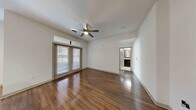 Located in Houston's vibrant Montrose neighborhood, this one-bedroom, three-bathroom residence at City Place Montrose offers a well-designed, single-floor layout that maximizes both comfort and functionality. Rich, dark hardwood flooring runs throughout the main living areas, lending warmth and a polished aesthetic to the space.

The open-concept living room is bathed in natural light thanks to full-length French doors topped with transom windows, which also provide access to the outdoors. A ceiling fan overhead adds comfort and a clean architectural detail to the room.

The kitchen is a standout feature, showcasing dark espresso cabinetry, granite countertops, stainless steel appliances including a refrigerator, range, microwave, and dishwasher, and a large central island with pendant lighting above — ideal for casual dining or meal prep.

The bedroom offers a comfortable, private retreat with plush carpeting, a ceiling fan, and a bright window that fills the room with natural light. Three bathrooms serve the unit, including one with a soaking tub framed by large-format neutral tile. Additional spaces include carpeted areas well-suited for flexible use. The clean, neutral color palette throughout creates a bright and welcoming atmosphere.