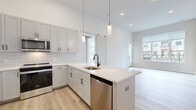 This well-appointed one-bedroom, one-bathroom residence at 8000 Crescent Cir in Randolph, NJ offers a thoughtfully designed open-concept layout. The combined kitchen and living area serves as the heart of the home, showcasing soaring ceilings that amplify the sense of space. The kitchen is outfitted with white shaker cabinetry, a classic subway tile backsplash, a large quartz peninsula with an undermount sink and matte black faucet, stainless steel appliances, and stylish cylindrical pendant lighting. Light-toned hardwood-style flooring flows throughout, enhancing the bright, airy ambiance. The living area receives generous natural light through wide windows overlooking the landscaped community grounds. The spacious bedroom features a wall of large windows with outdoor views and connects to an expansive walk-in closet with built-in shelving and hanging rods. The bathroom presents a refined, minimalist aesthetic with large-format tile flooring, a floating wood-toned vanity, quartz countertop, and a backlit mirror. Additional highlights include a private patio with iron fencing, in-unit laundry, extra closet storage, and a utility room, completing this modern and functional residence.