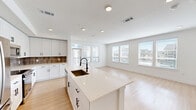 Located in Georgetown, TX, this modern 2-bedroom, 2-bathroom home offers a thoughtfully designed single-floor layout finished with clean, contemporary details throughout. Light wood-tone flooring runs seamlessly across the entire space, complementing the crisp white walls and creating a bright, cohesive aesthetic.

The open-concept kitchen and living area serves as the heart of the home. The kitchen features white shaker-style cabinetry, a warm-toned tile backsplash, stainless steel appliances, and a large center island with a white quartz countertop and an undermount sink with a matte black faucet. The adjoining living area is bathed in natural light from multiple windows, with a private entry door adding convenience. Built-in shelving near the kitchen provides additional storage and display space.

The primary bedroom is a well-proportioned retreat featuring a bank of windows that fill the room with natural light. Its en-suite bathroom is appointed with a dual-sink white vanity, matte black fixtures, a framed mirror, a glass-enclosed walk-in shower, and direct access to a spacious walk-in closet with built-in shelving. The second bedroom includes a ceiling fan and ample natural light. The second bathroom offers a single-sink vanity with overhead cabinetry and matte black hardware, maintaining the home's consistent modern style.