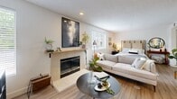 Located at 1710 NE Multnomah St in Portland's vibrant Lloyd District, this one-bedroom, two-bathroom unit offers a thoughtfully designed single-floor layout that maximizes every inch of its intimate footprint. The open living area serves as the heart of the home, anchored by a tiled fireplace with a wood mantel and flanked by windows that invite natural light. Light wood-toned flooring flows throughout, complementing the neutral wall palette and creating a warm, cohesive ambiance. The bedroom area is integrated seamlessly with the living space, offering a cozy and functional arrangement. The kitchen is well-equipped with rich cherry wood cabinetry, granite-style countertops, stainless steel appliances including a full refrigerator, electric range, dishwasher, and a skylight overhead that brightens the cooking space. A dining area with a butcher-block style table sits adjacent to the kitchen. Two bathrooms provide added convenience — one featuring a cherry vanity with stone countertops and a large mirror, while the second offers a full tub and shower with clean white tile. The overall design balances practicality with warmth, making this a comfortable and efficient Portland residence.