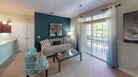 This single-floor residence offers a thoughtfully designed layout across a generous footprint. The living room serves as the heart of the home, featuring plush carpeting, a bold teal accent wall, and sliding glass doors that open to a private balcony with outdoor views, filling the space with natural light. Adjacent areas provide additional flexible living space, ideal for a dining or sitting area, with open sightlines into the hallways and secondary rooms.

The kitchen is well-equipped, featuring rich dark cherry wood cabinetry, light countertops, black appliances including a range and built-in microwave, a double sink, and tile flooring — offering ample storage and workspace for cooking.

The primary bedroom is a serene retreat, highlighted by a large arched window overlooking lush greenery, soft carpet, and generous room for furnishings. The second bedroom also enjoys abundant natural light through multiple windows and is equally well-sized.

Both bathrooms are finished with tile flooring, tub-shower combinations with decorative curtains, dark wood vanities topped with light countertops, and large mirrors. A dedicated in-unit laundry room houses a full-size washer and dryer alongside a water heater, adding everyday convenience to this comfortable and cohesive residence.