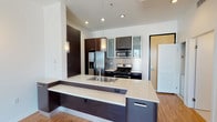 Located in the vibrant West Hollywood neighborhood of Los Angeles, this modern single-floor unit at 7921 Waring Ave offers a sleek, contemporary design throughout. The open-concept kitchen is a standout feature, anchored by a large island with a crisp white quartz countertop, an undermount sink, and dark espresso cabinetry that extends throughout. Stainless steel appliances — including a gas range, built-in microwave, and French door refrigerator — are complemented by a mosaic tile backsplash and frosted glass upper cabinets, adding a refined, modern touch. Pendant lighting over the island and warm wood-look flooring complete the kitchen's polished aesthetic. The bathroom is clean and well-appointed, featuring large-format light tile flooring, a full tub-shower combination with sliding glass doors, and a dark wood vanity with an integrated sink and generous storage. The bedroom offers plush carpeting, crisp white walls, and a sliding glass door that opens directly onto a private balcony, inviting abundant natural light and offering open views of the surrounding Los Angeles cityscape and lush treetops. The overall ambiance of the unit is contemporary and well-finished, delivering a comfortable urban living experience in a prime Los Angeles location.