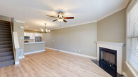 Located at 10 Fieldstone Common in Tolland, Connecticut, this well-appointed 2-bedroom, 3-bathroom home is thoughtfully laid out across three floors. The ground level features an attached garage with an epoxy-coated floor and automatic opener, along with a utility room and convenient bathroom. The main living floor showcases an open-concept kitchen and living room combination finished with light hardwood-style flooring, crown molding, and a classic fireplace framed by a white mantel. The kitchen is equipped with white shaker cabinetry, a stainless steel dishwasher, white quartz countertops, and a tile backsplash, while the living area benefits from natural light through large windows and a ceiling fan overhead. The upper floor is home to two generously sized bedrooms, each carpeted and fitted with ceiling fans and crown molding. The expansive primary bedroom offers abundant natural light through dual windows. A dedicated walk-in closet with wire shelving provides ample storage. Three bathrooms serve the home, including a full bath with a soaking tub and tiled surround, and a stylish vanity bathroom featuring shaker-style cabinetry with black hardware, quartz countertops, and warm vanity lighting. Neutral taupe tones and clean white trim carry a cohesive, modern aesthetic throughout.